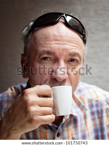 Portrait of smart old man drinking cup of coffee