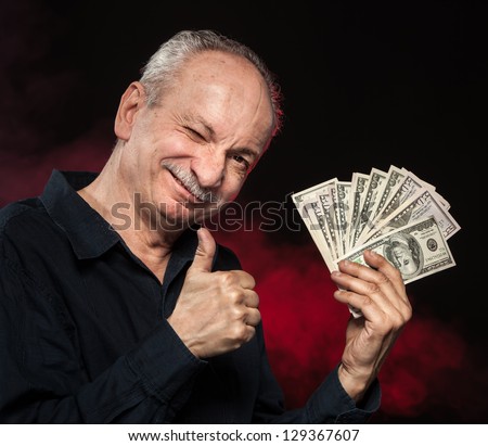 Lucky old man holding with pleasure group of dollar bills