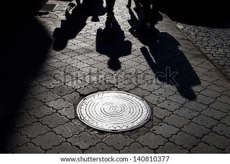 Shadows of people walking street in morning light
