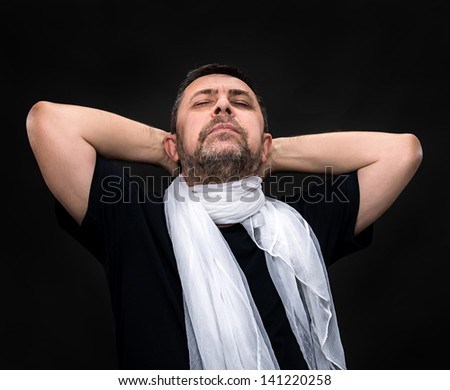 Portrait of a handsome man with a white scarf and closed eyes on a dark background