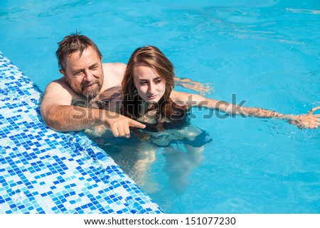 Happy family. Father and daughter swimming in the pool on a sunny day.