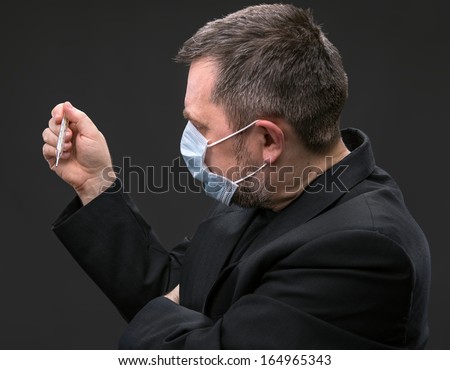Illness. Man in medical mask with a thermometer