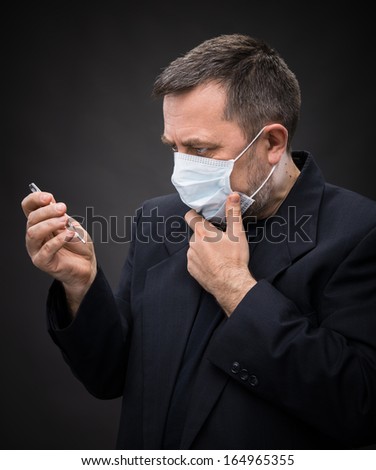 Illness. Man in medical mask with a thermometer