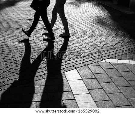 Shadows of people walking street in morning light