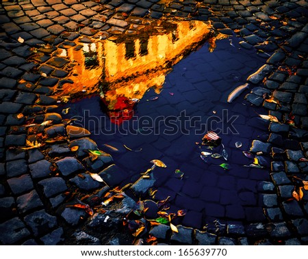 Morning in the old town. Reflection of buildings in a puddle of water. Intentional color shift and contrast