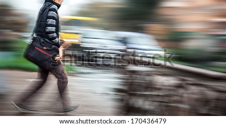 Man crossing the street at a crosswalk. Intentional motion blur