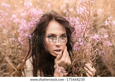 Portrait of beautiful freckled girl among the flowers. Intentional color shift