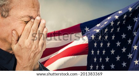 Veteran. Portrait of an elderly man with face closed by hand on USA flag background. Intentional color shift
