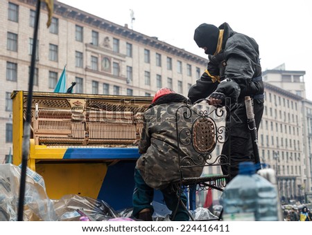 KIEV, UKRAINE - Feb 12, 2014: Mass anti-government protests in the center of Kiev. Barricades, ruin and chaos on Hrushevskoho St. Pianist plays the piano at the barricade