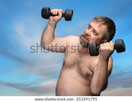 Elderly man exercising with dumbbells against the sky with clouds