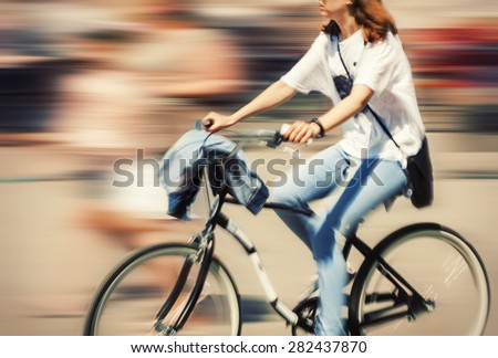 Hot day in the city. Cyclist in traffic on the city roadway. Intentional motion blur