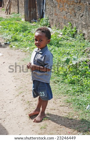 WASSINI ISLAND, KENYA, AFRICA, DECEMBER 2008: Little African boy in a poor fishermen\'s village stands on the way of a humanitarian group