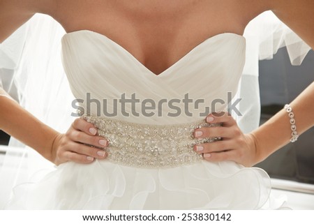 bride in luxury dress with plunging neckline, arms akimbo