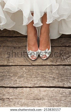 bride white open toe shoes decorated with bow and strass on wood boards