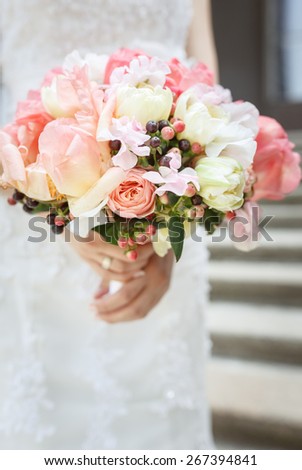 Beautiful wedding bouquet of pink and white peony flowers in hands of the bride