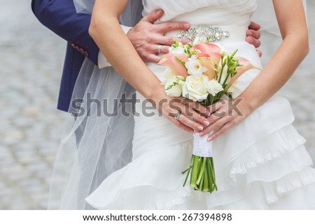Beautiful wedding bouquet of rose Vendella, calla and freesia flowers in hands of the bride