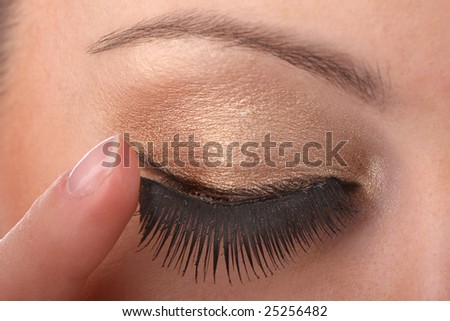 closeup of female applying fake eyelash on eye