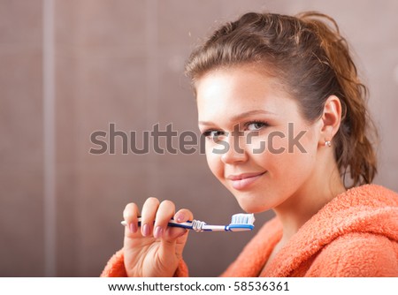 pretty woman in bath holding tooth brush and looking at camera