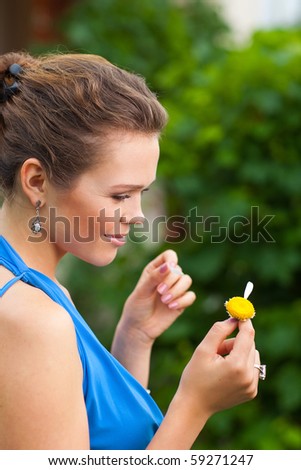 attractive young adult holding camomile and tearing off petals