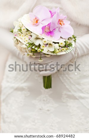 bride in white clothes holding beautiful wedding bouquet with orchids
