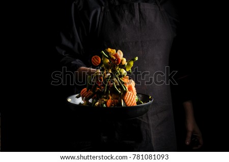 Flying mixed vegetables on a pan. Diet healthy food. Black background for copy text.