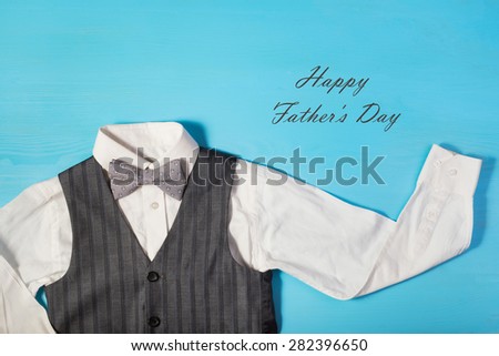 Greeting card for Dad\'s Day, white shirt, gray vest and a bow tie on a bright blue background, and text \