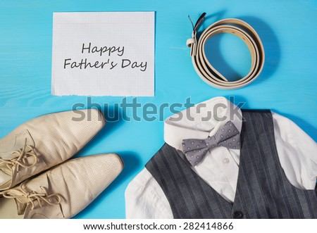 Greeting card for Dad\'s Day, a white shirt,  men\'s shoes, gray vest and bow tie, a belt and a sheet of paper with text  \
