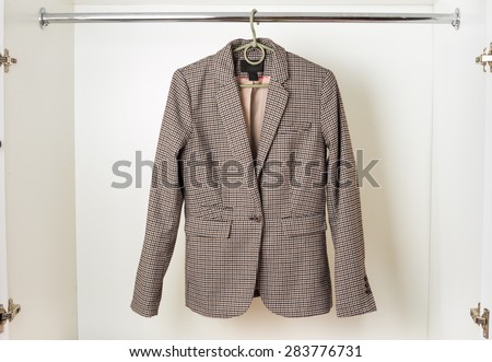 Women's classic English-style jacket hanging on a hanger in the white closet