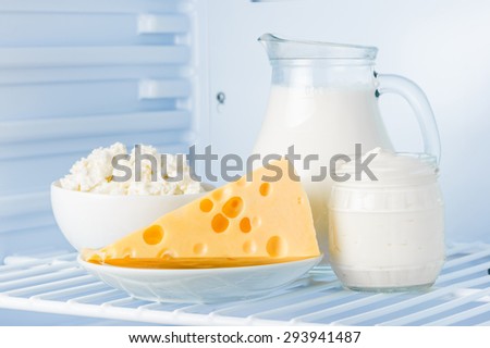 tasty healthy dairy products in the refrigerator: sour cream in the bank, cottage cheese in  bowl,  cheese  and milk in a jar