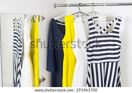 a series of bright modern fashion women\'s dresses on hangers in a white cupboard for summer and spring