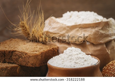 Wheat flour, sliced bread, wheat ears on an old wooden background