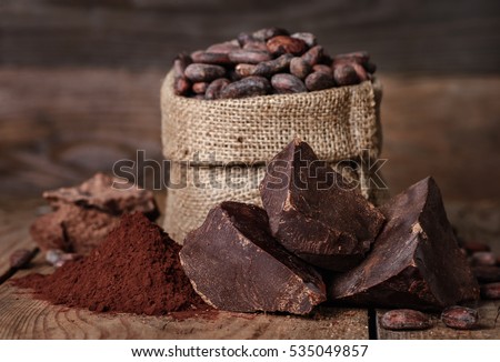 unsweetened baking block chocolate, Cocoa powder and cocoa beans on old wooden background