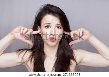 Beautiful girl covering hear ears, making a silly face