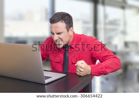 Angry businessman in the office looking at lap top
