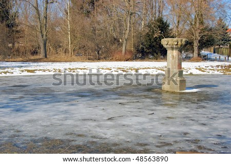 Small pond been cold with stone column to the right and angel faces