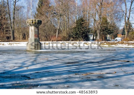 Small pond been cold with stone column to the left and angel faces