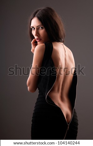 beautiful woman in a black dress with a gray background