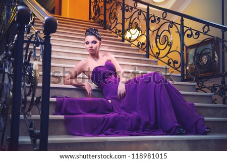 woman in a long dress is sitting on the stairs in the hotel lobby