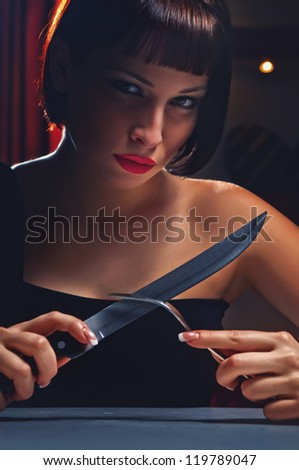 beautiful woman in a black dress with a knife and fork in hand