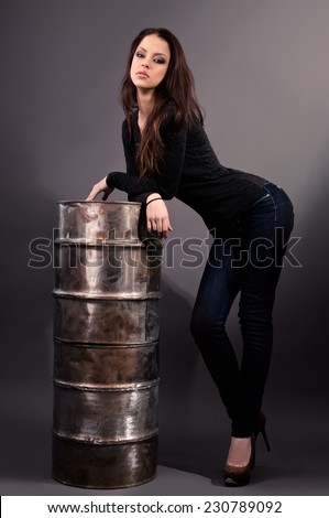 beautiful girl in jeans standing near an iron barrel