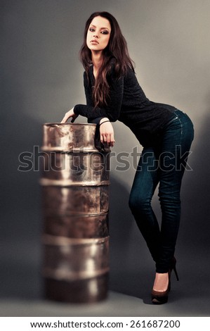 beautiful girl in jeans standing near the iron barrel.