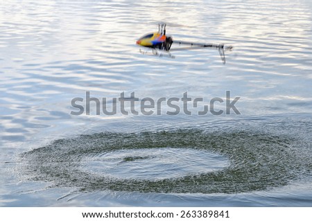 Flying remote controlled helicopter in motion over the water