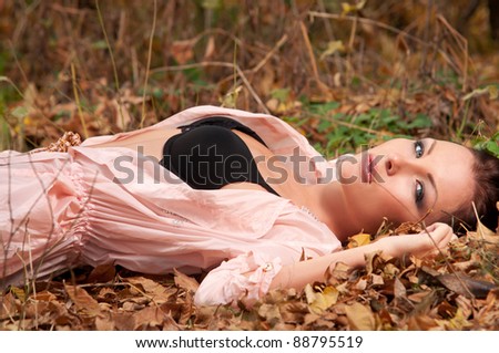 woman in elegant clothes lying on the leaves