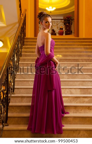 young woman in a long dress lying on the stairs in the hotel lobby