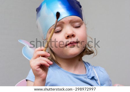 Little girl artist with a brush in hand in a rubber cap