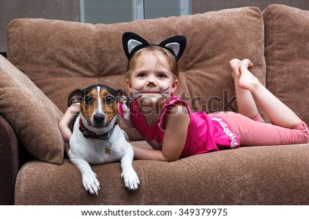 little girl with cat face painting embrace her dog
