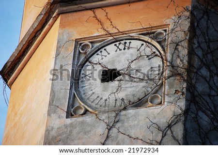 The close up of an old tower overgrown with ivy with the broken clock