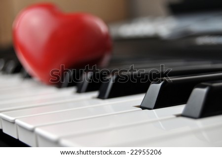 Red wooden heart on a piano keyboard