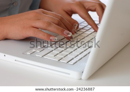A woman with beautiful nails typing on a laptop