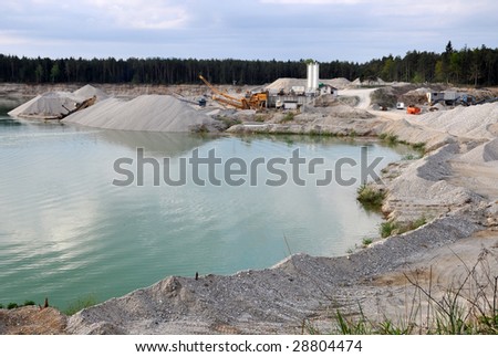 Stone quarry with silos, conveyor belts, and other mining equipment by the water